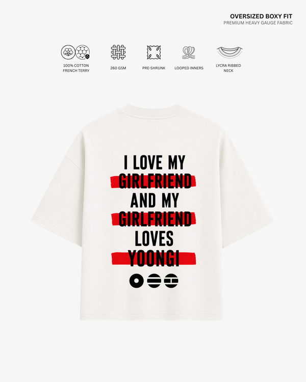 A white oversized boxy-fit T-shirt shown from the back, featuring a humorous printed slogan in black text with red highlight bars and black emoji faces. The image includes feature icons and text at the top detailing the fabric's properties.
